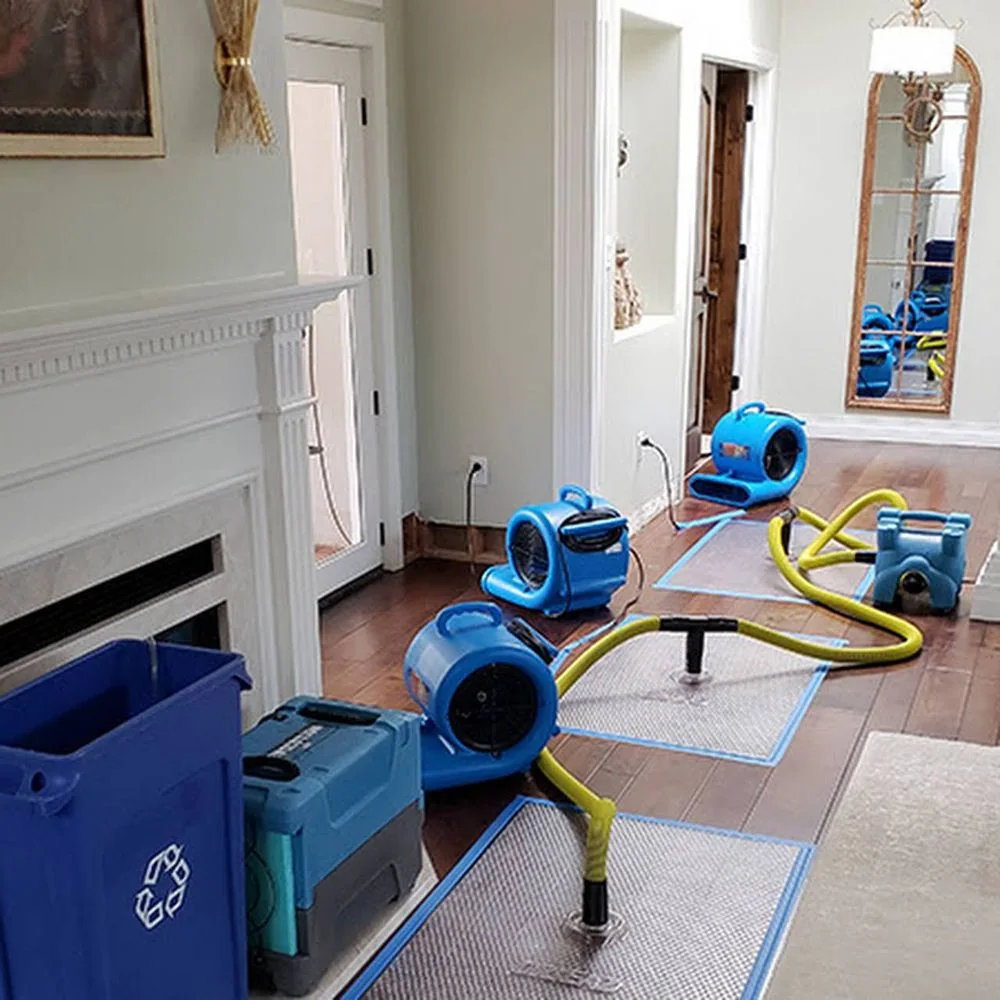 Professional air movers and floor drying equipment inside a water-damaged home